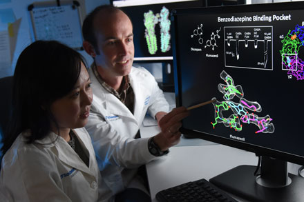 2 medical professionals point to cellular data on computer display