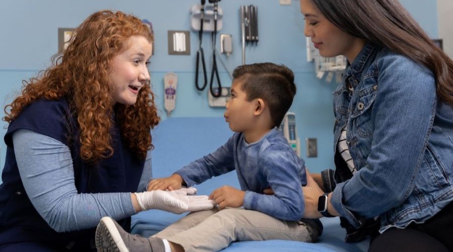 red haired APP comforts child and his mother in exam room