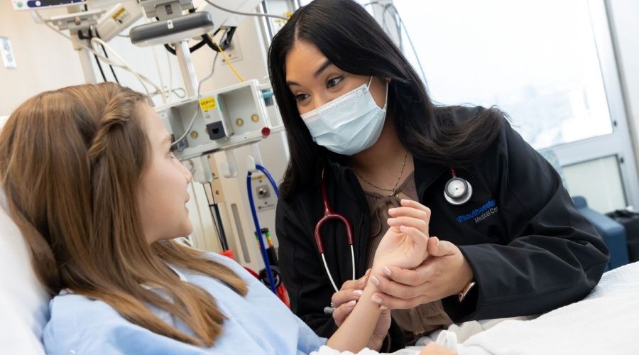 APP wearing mask holds child's hand in her hospital room