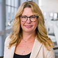 Heather Kitzman: smiling woman with glasses and long blonde hair wearing cream blazer and black shirt