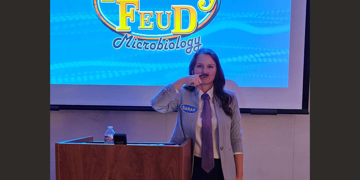 Faculty Feud host standing at podium