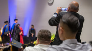 An audience member snaps a pic of graduates crossing the stage.