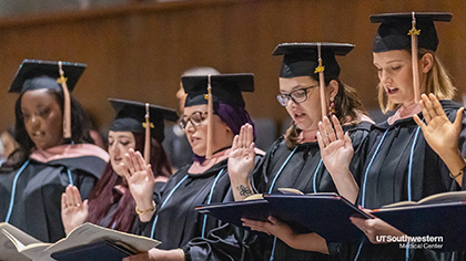 5 students in full graduation attire, raise their right hands while taking an oath.