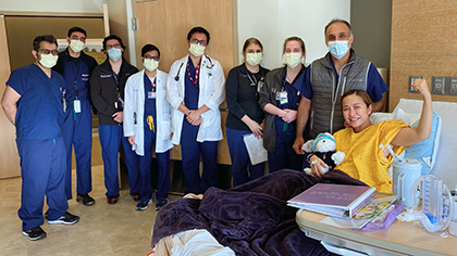 Group of masked healthcare providers around a patient bed. Mom in the bed is holding a stuffed animal.