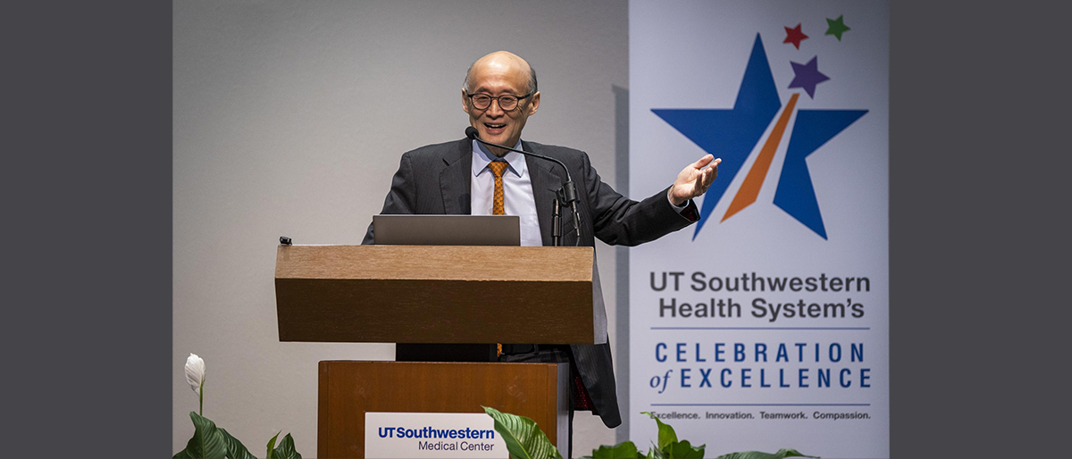 Smiling, balding man wearing a dark suit, light-colored shirt, and orange tie. UT Southwestern Health Systems Celebration of Excellence, Excellence, Innovation, Teamwork, and Compassion