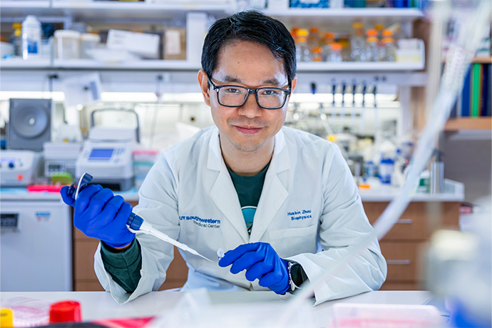 Smiling lab technician holding a test tube and dropper.