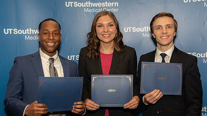 Three people holding certificates