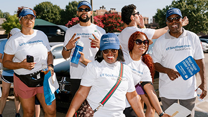 diverse group of six people in UT Southwestern T-shirts and hats outside at Juneteenth event, 3 men, 3 women