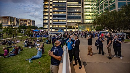 exterior of UTSW hospital with large groups of employees and visitors wearing sunglasses looking at the sky during eclipse