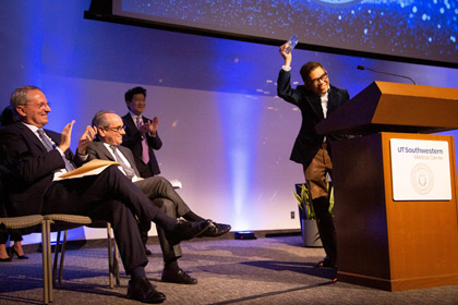 Man holding up glass award on a stage