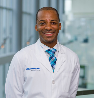 Mandell Butler Jr., UTSW Nurse and Lieutenant in the Army Reserves Man with short cropped hair in white coat, blue tie, smiling