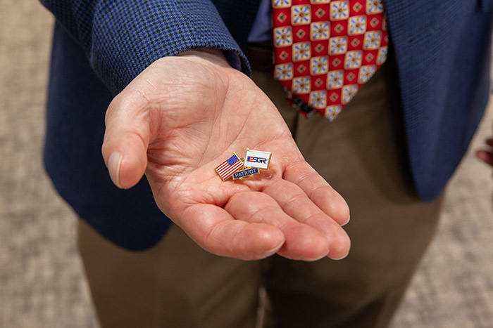 Drs. Halm and Agusala were presented with a lapel pin in addition to a certificate as part of the recognition of their Patriot Awards. Open palm holding ESCR Patriot pin