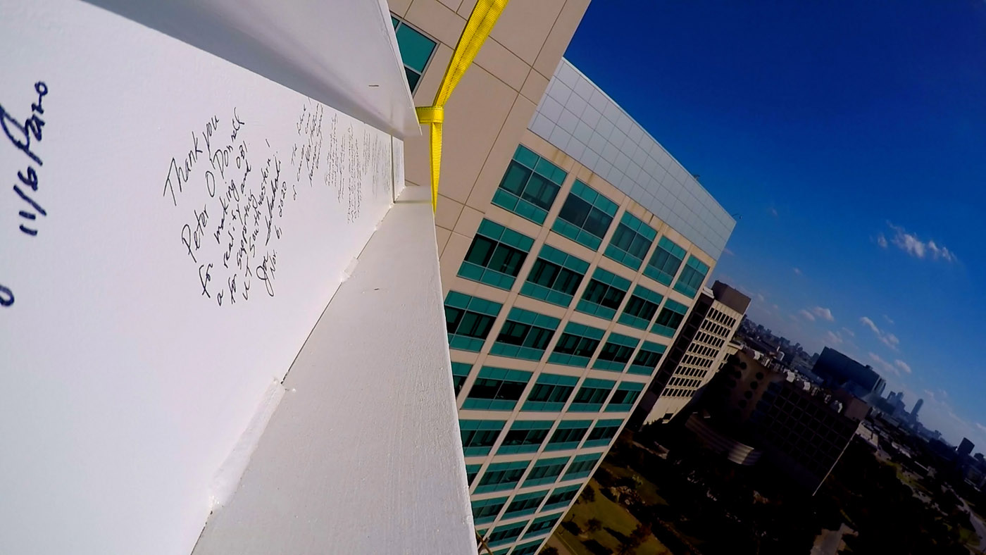 During the Nov. 30 Topping Out Ceremony, a beam covered in messages written by leaders, faculty, and staff was added to the construction. Beam being lowered down with writing on it