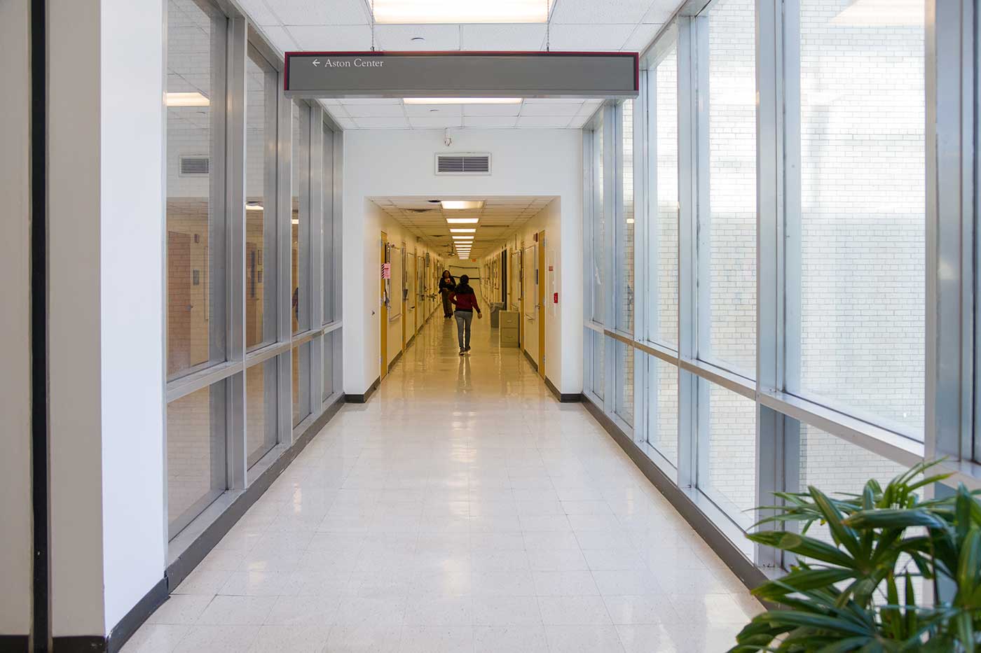The Aston Ambulatory Care Center is currently undergoing a large renovation. Long hallway with person walking down it, lined by windows