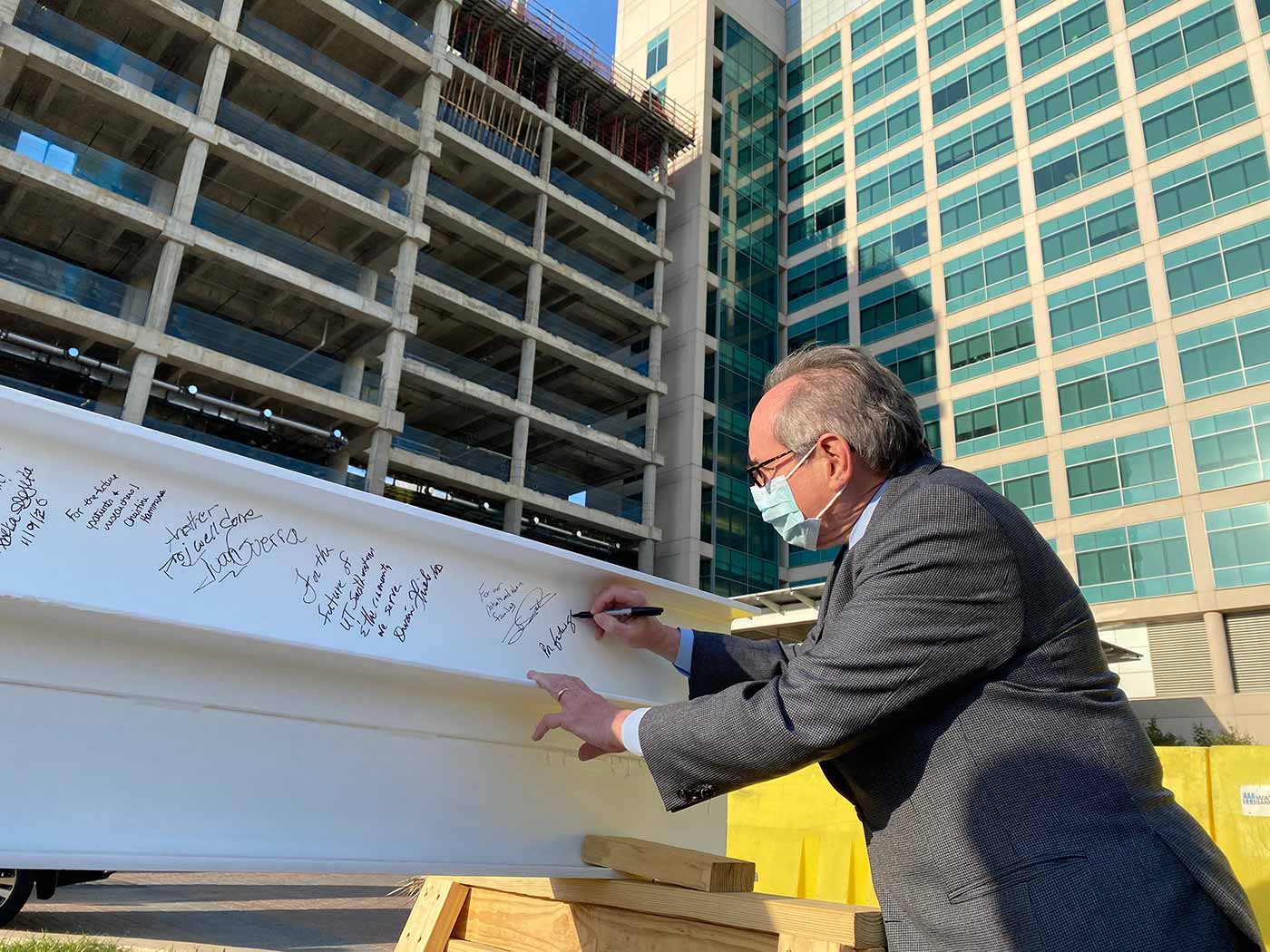 President Dr. Daniel K Podolsky writes a message on steel beam used in construction.