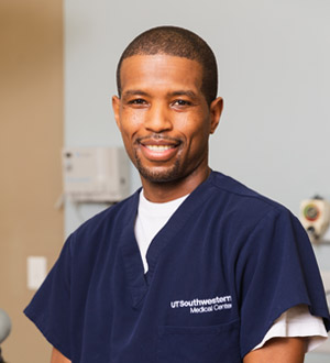 Omar Milliner Man with shaved head wearing scrubs
