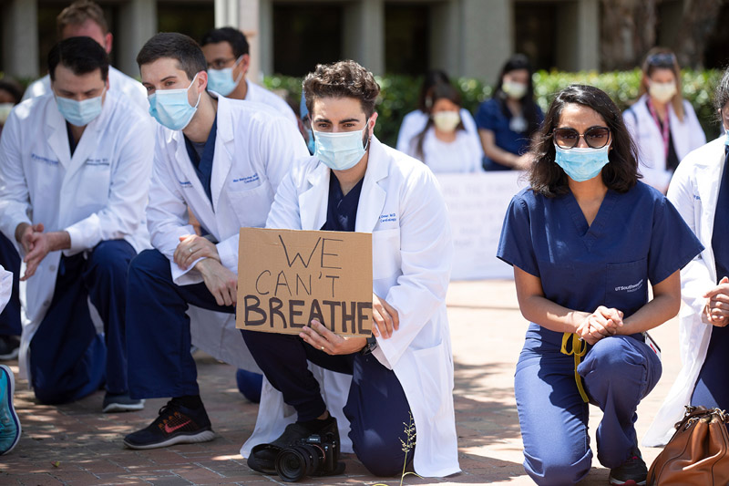 Cardiology fellow Dr. Wally Omar (center) People kneeling and holding signs