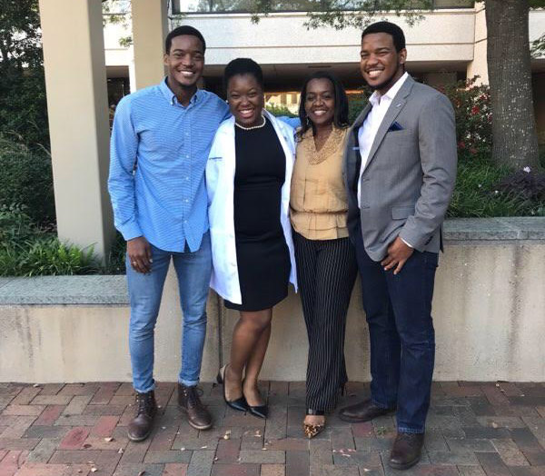 Ms. Constable (from left) with her brother Daniel, her mother Cordia, and her brother Shane. Four people standing on UTSW campus