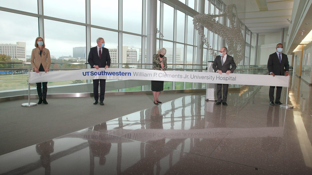 Cutting a ribbon to celebrate the official opening of the hospital’s new wing is Becky McCulley, VP of Clinical Programming and Facility Development, joined by (from left): Thea Vanderhill, Assistant VP of Clinical Design and Transition Planning; Dr. John Warner; Dr. Daniel K. Podolsky; and Robert Nickerson, Director of Major Capital Improvement Projects. Three people spread out, cutting large ribbon