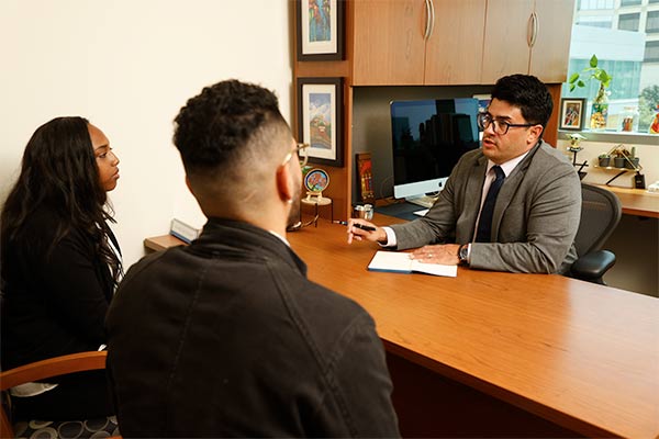 Arnaldo Díaz Vázquez man sits at desk across from students