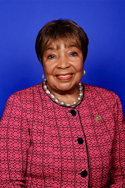 U.S. Rep. Eddie Bernice Johnson woman with short cropped hair wearing pink and black suit against blue background