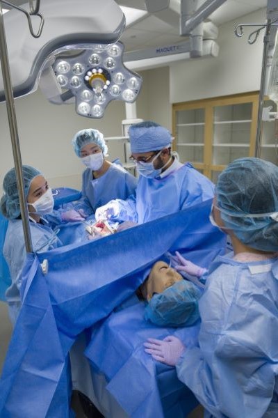 4 medical students practice surgery on manikin in Sim Center
