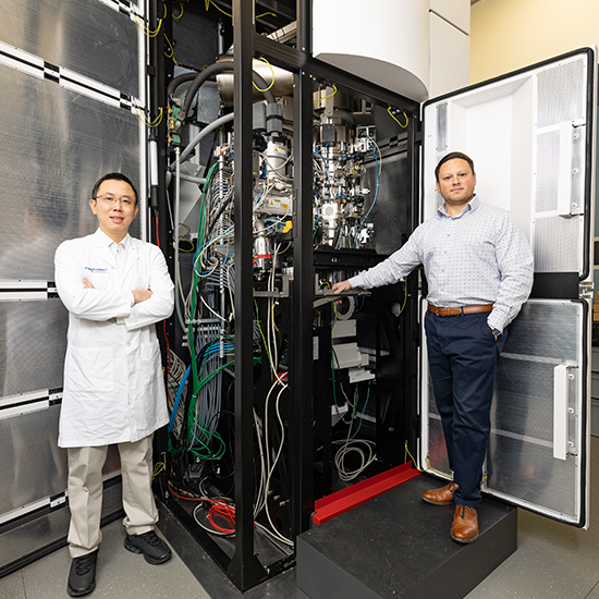 Drs. Bai and Stoddard Two men standing next to a large computer.