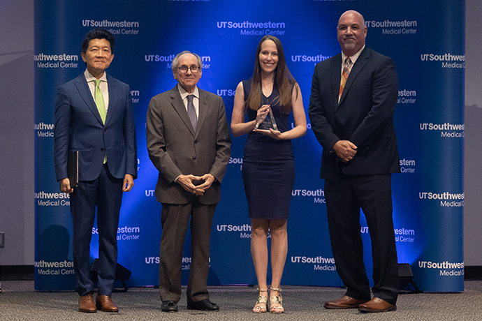 A woman holding her award poses with the presenters.