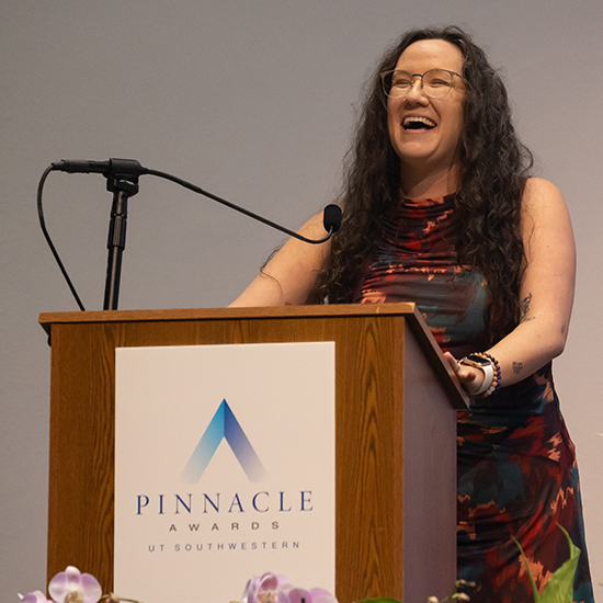 A speaker at the Pinnacle Awards UT Southwestern pedistal laughs.