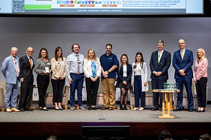 Eleven people gather onstage with the poster winner.