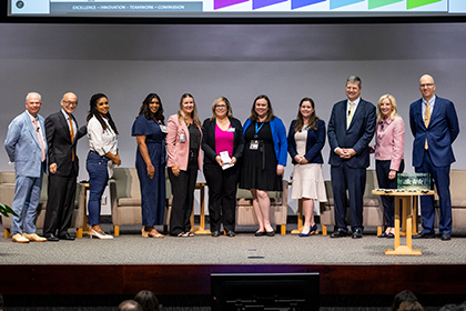 Ten people gather onstage with the poster winner.