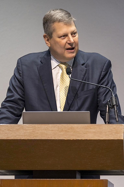 Dr. Efron Man with gray hair, wearing a dark suit, white shirt, and yellow tie, speaks from podium at UT Southwestern Health Systems Celebration of Excellence.