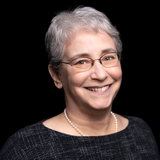Dr. Conaway Smiling woman with short gray hair, wearing a black top, pearls, and glasses.