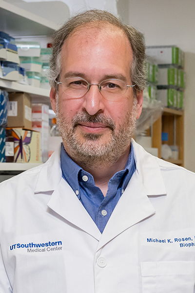 Dr. Rosen Serious man with gray receeding hair, beard, and mustache, wearing a white UT Southwestern Medical Center lab coat.
