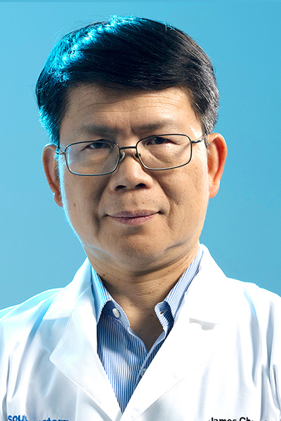 Zhijian “James” Chen, Ph.D. Man with thick dark hair, wearing a white UT Southwestern lab coat over a blue shirt and glasses.