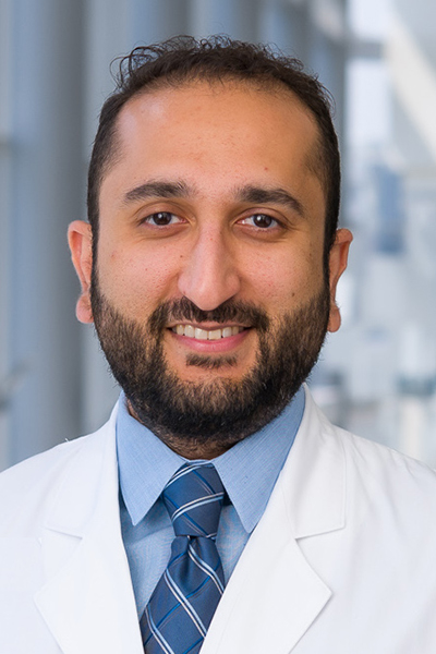 Jay Pandya headshot; man with dark hair and beard wearing white coat, blue shirt and tie