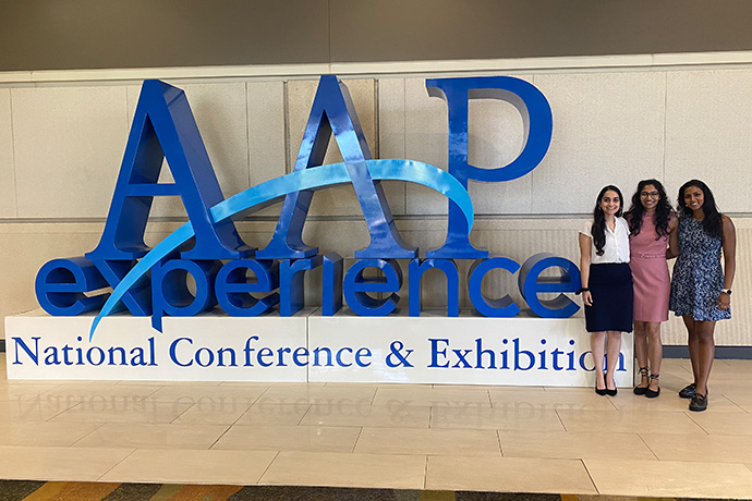 3 female students present research findings on stage