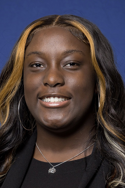Zahria Griggs headshot; Black woman with wavy long hair wearing black shirt and hoop earrlings