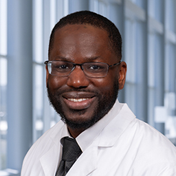 Dr Addison wearing glasses and a white lab coat with a black necktie