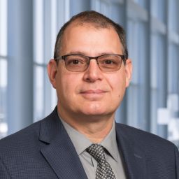 a man with glasses wearing a dark suit
