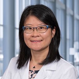 Dr. Jiesin Wang wearing a white lab coat, standing in the CUH lobby