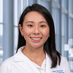 Dr. Shuyao Zhang wearing a white lab coat standing in the CUH lobby