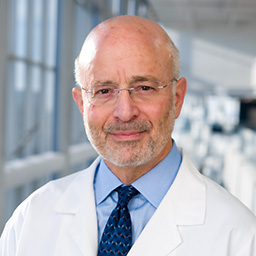 Dr. David Auerbach wearing a light blue shirt and blue patterned tie standing in the Clements University Hospital lobby