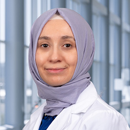 Dr. Batul Bat wearing a light purple hajib and a white lab coat standing in the Clements University Hospital Lobby