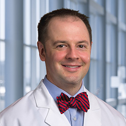 Dr. Michael Bowen wearing a light blue shirt with a red stripped bow tie and a white lab coat