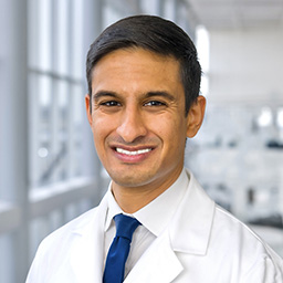 Dr. Shanup Dalal wearing a checkered shirt and white lab coat