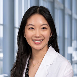 Dr. Monica Li wearing a white lab coat and black shirt standing in the Clements University Hospital lobby
