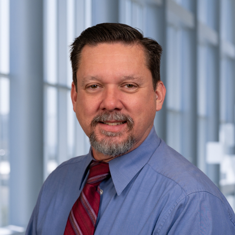 Vincent Merrill wearing a blue shirt with a red striped tie standing in the Clements University Hospital lobby