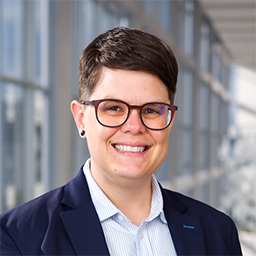 Dr. Megan Mullins wearing a light blue shirt and dark suit jacket standing in the Clements University Hospital lobby