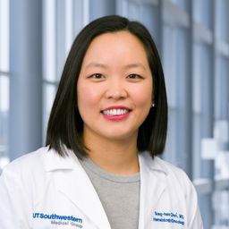 Dr. Sung-hee Choi wearing a grey shirt and a white lab coat standing in the Clements University Hospital lobby